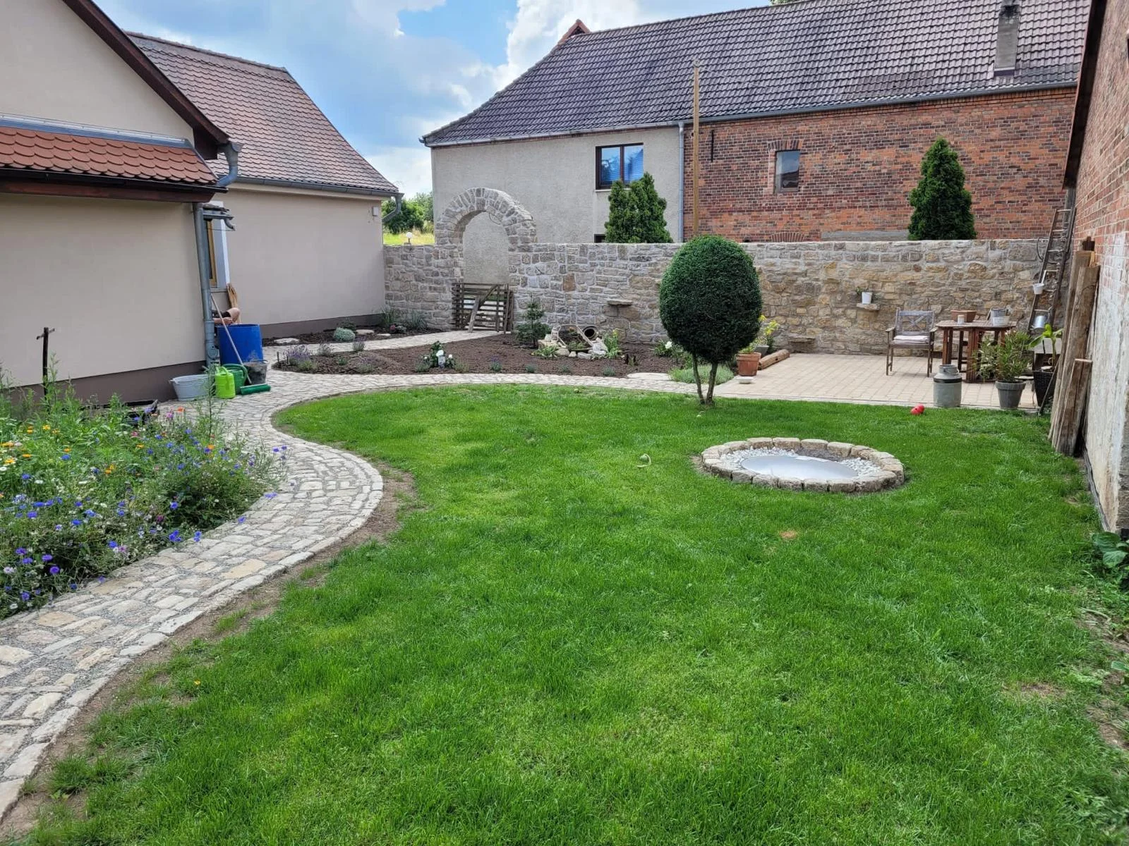 Fertiggestellter Garten mit Rasen, Natursteinweg und Natursteinmauer
