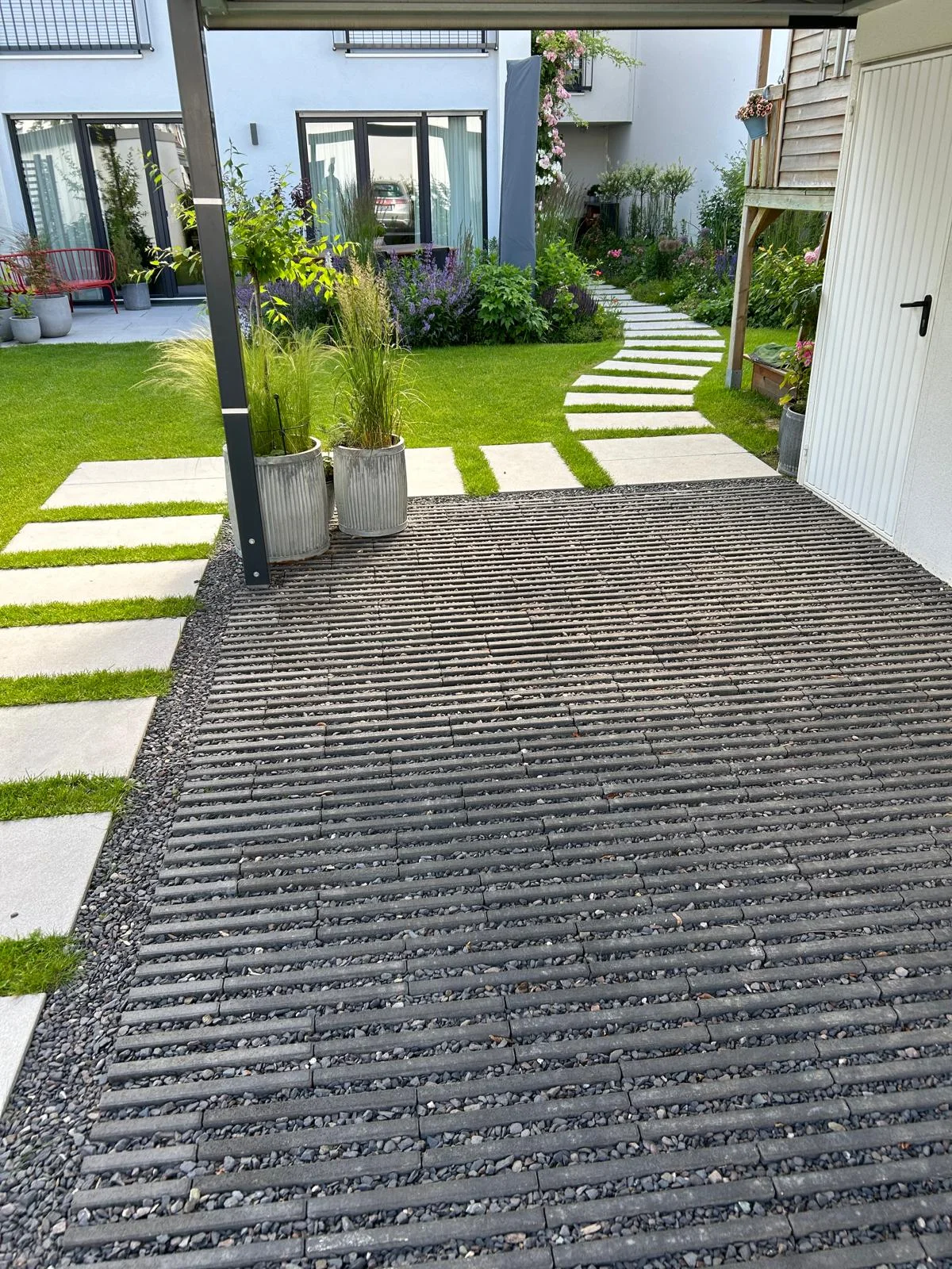 Moderner Garten mit Rasen, Schrittplatten, Staudenbeeten und Rasengitter-Stellfläche