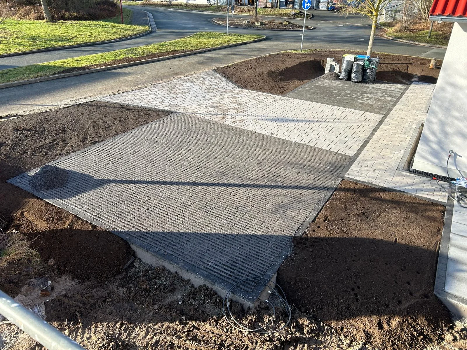 Gepflasterte Hofzufahrt mit Rasengittersteinen und hellem Betonpflaster