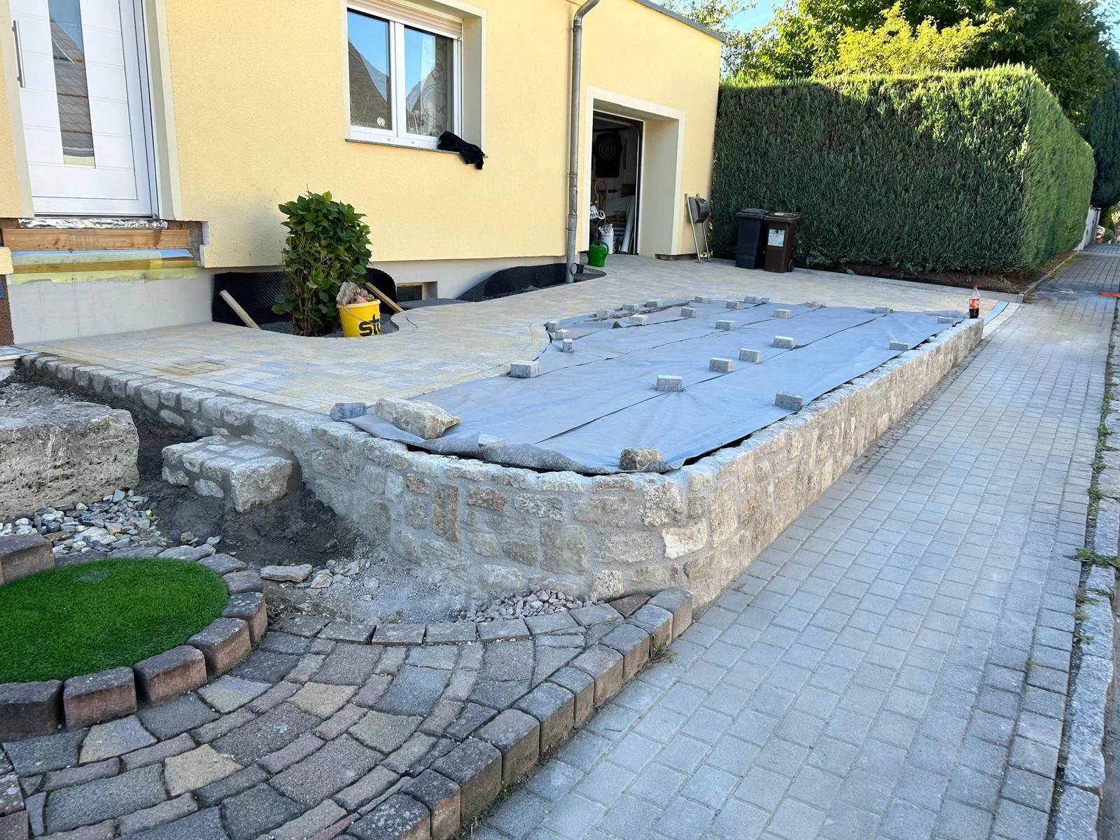 Sandstein-Einfassungsmauer entlang einer gepflasterten Hofzufahrt