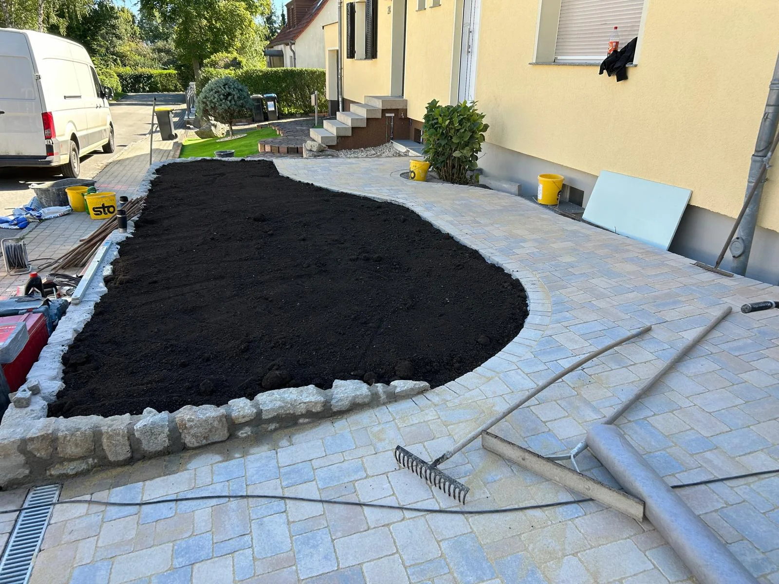Sandstein-Pflasterfläche mit geschwungenem Beet und Palisaden-Einfassung