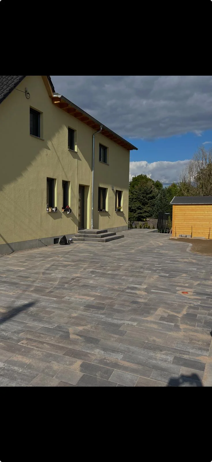 Großflächig gepflasterter Hof mit Mehrformat-Pflaster an einem Wohnhaus